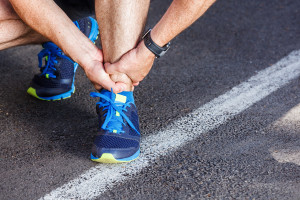 Broken twisted ankle - running sport injury. Male runner touchin